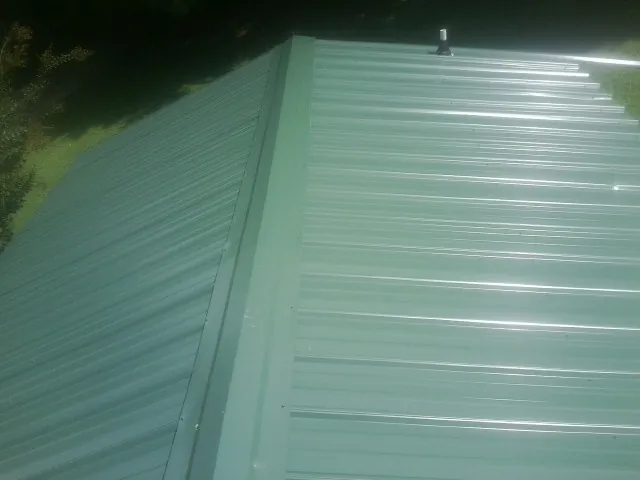 New green metal panels meeting at the ridge of a roof — Flat Roof Repair work by our crew in Bat Cave