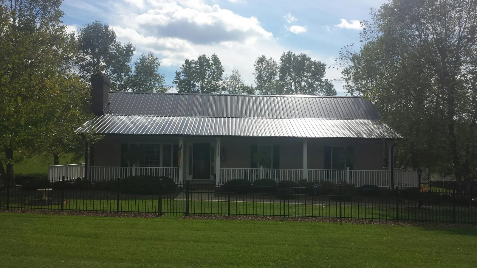Gray metal roof on a brick ranch with a full width front porch — Gutter Guard Installation work by our crew in Bat Cave